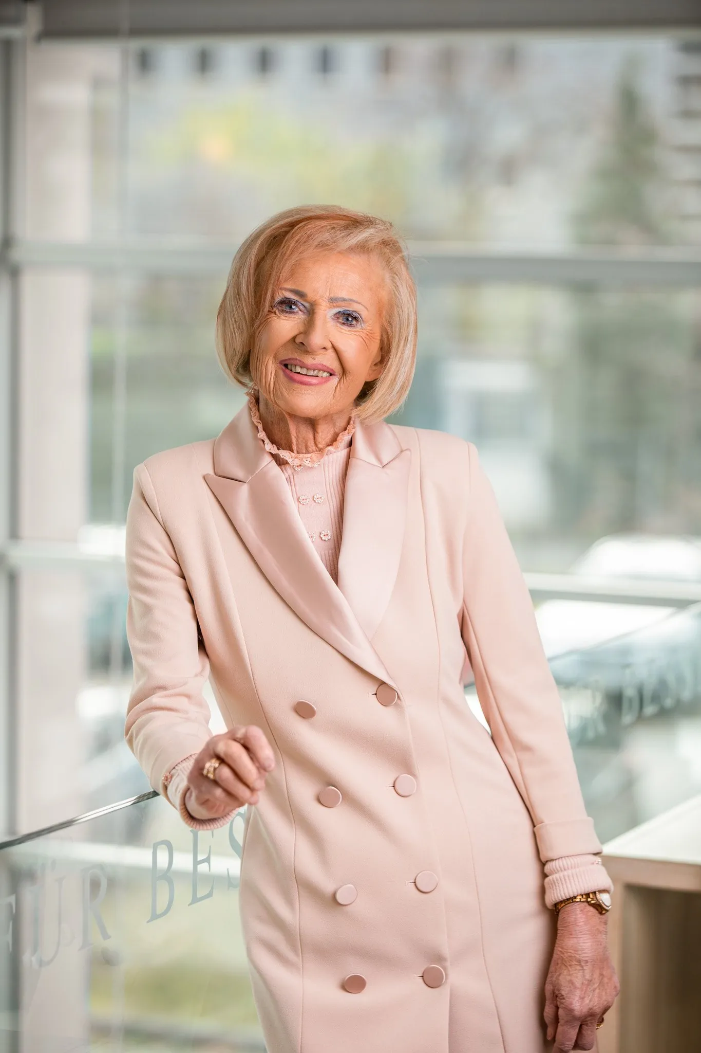 Mitarbeiterin im hellen Mantel am Bürofenster, Business Portrait