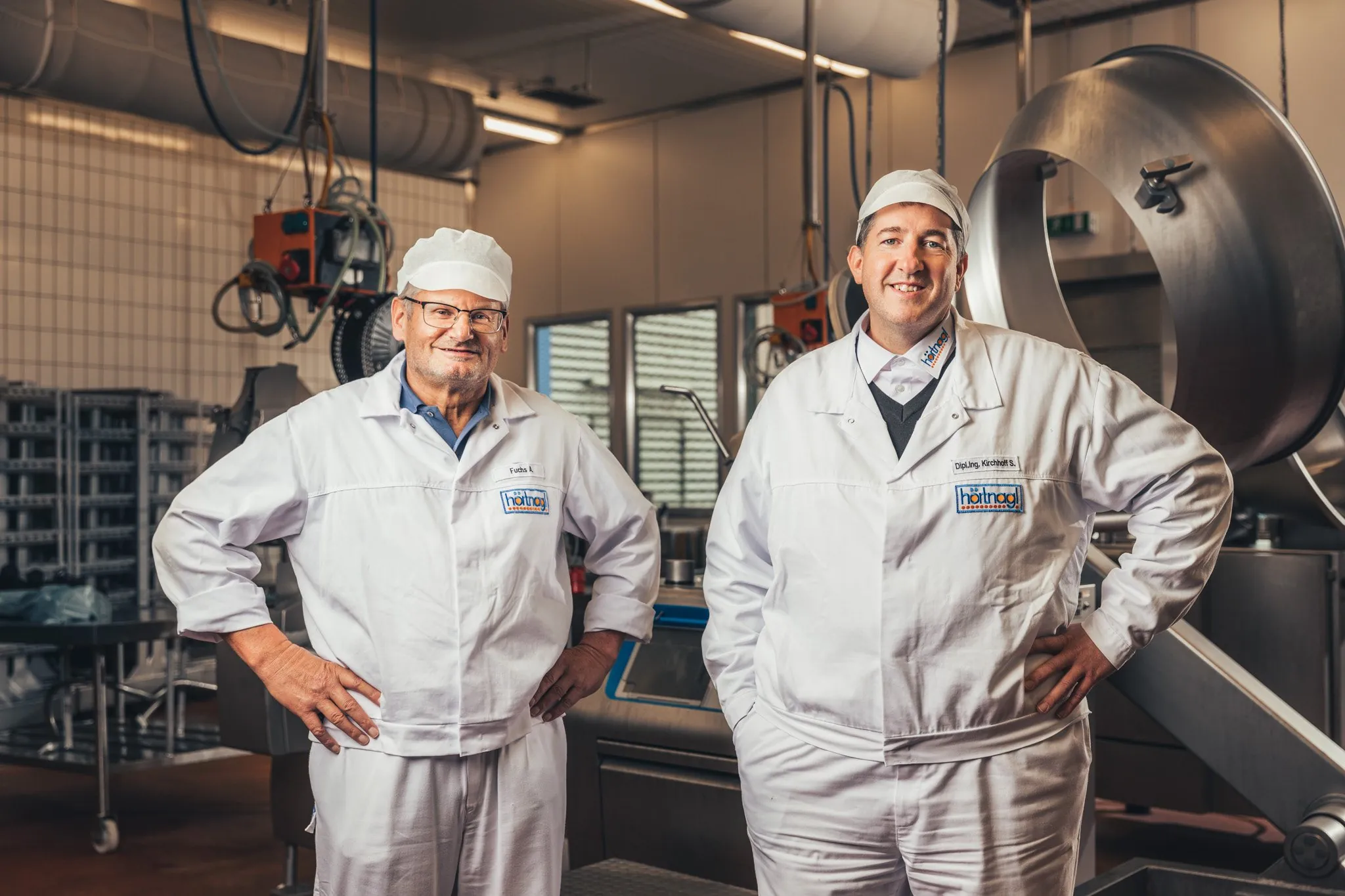 Zwei Mitarbeiter in Arbeitskleidung in der Produktion, Mitarbeiterportrait