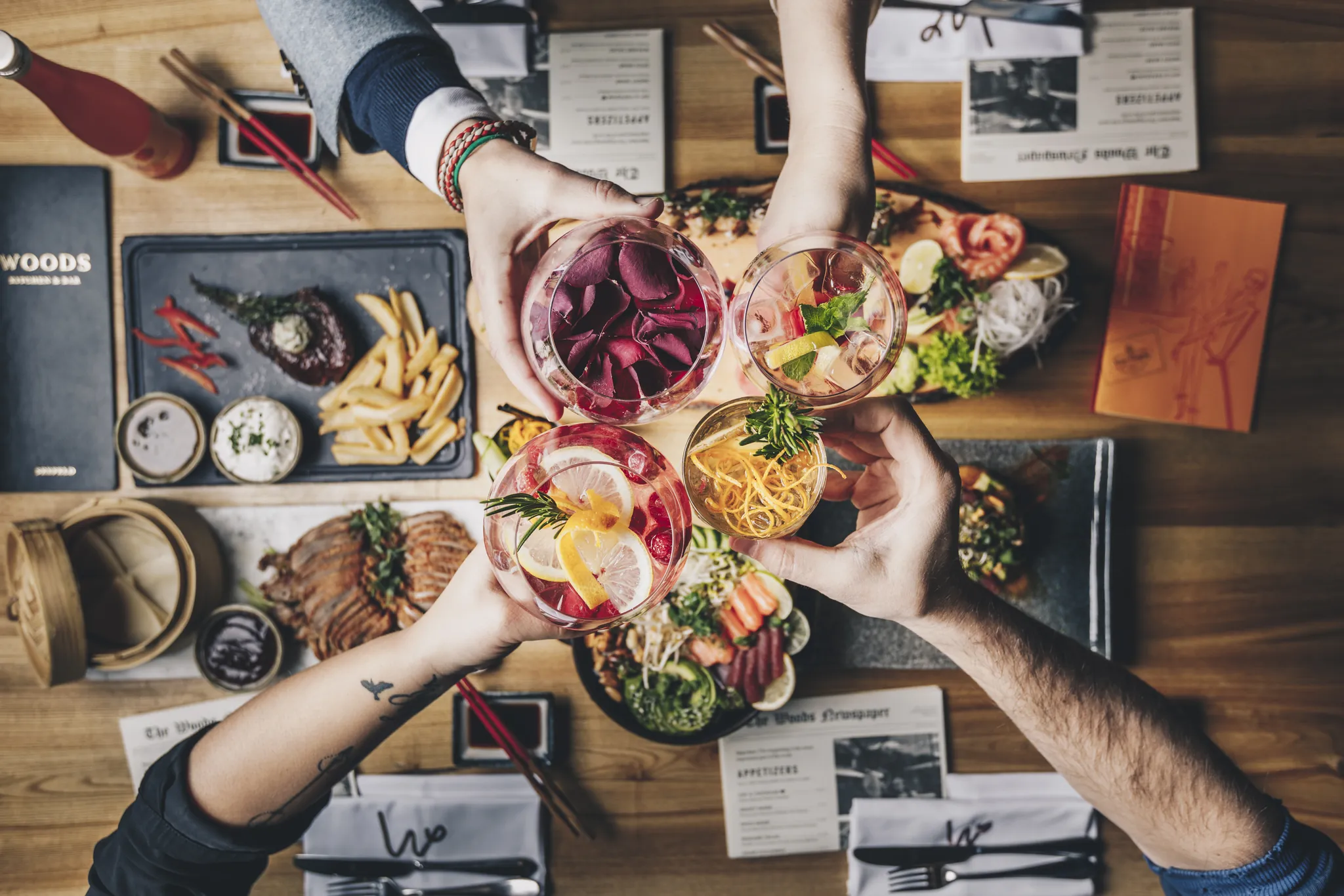 Gäste stoßen über einem gedeckten Tisch mit Sushi und Burgern an, Woods Seefeld