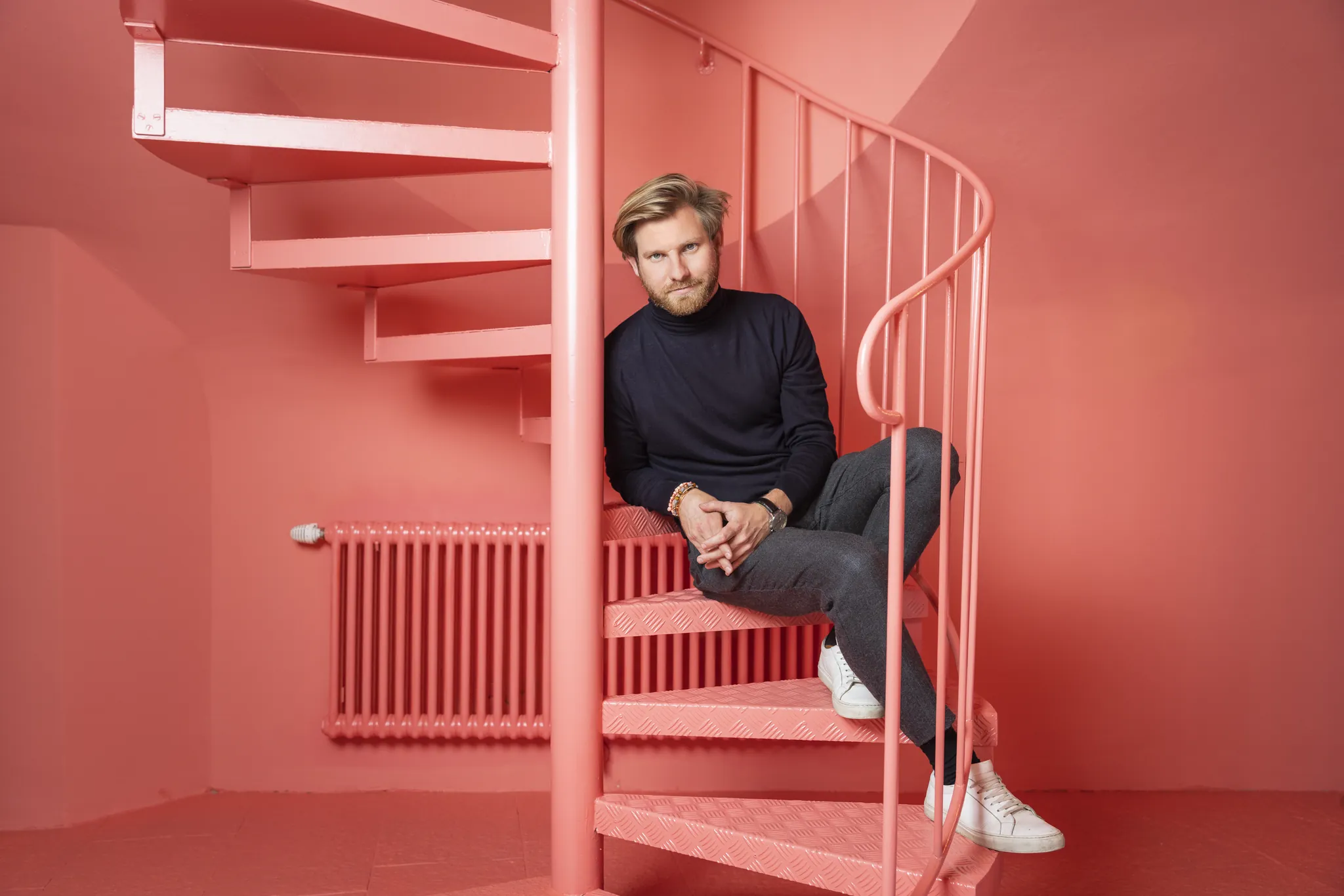 Business Portrait on Location: Mann auf einer roten Wendeltreppe in einem komplett roten Raum