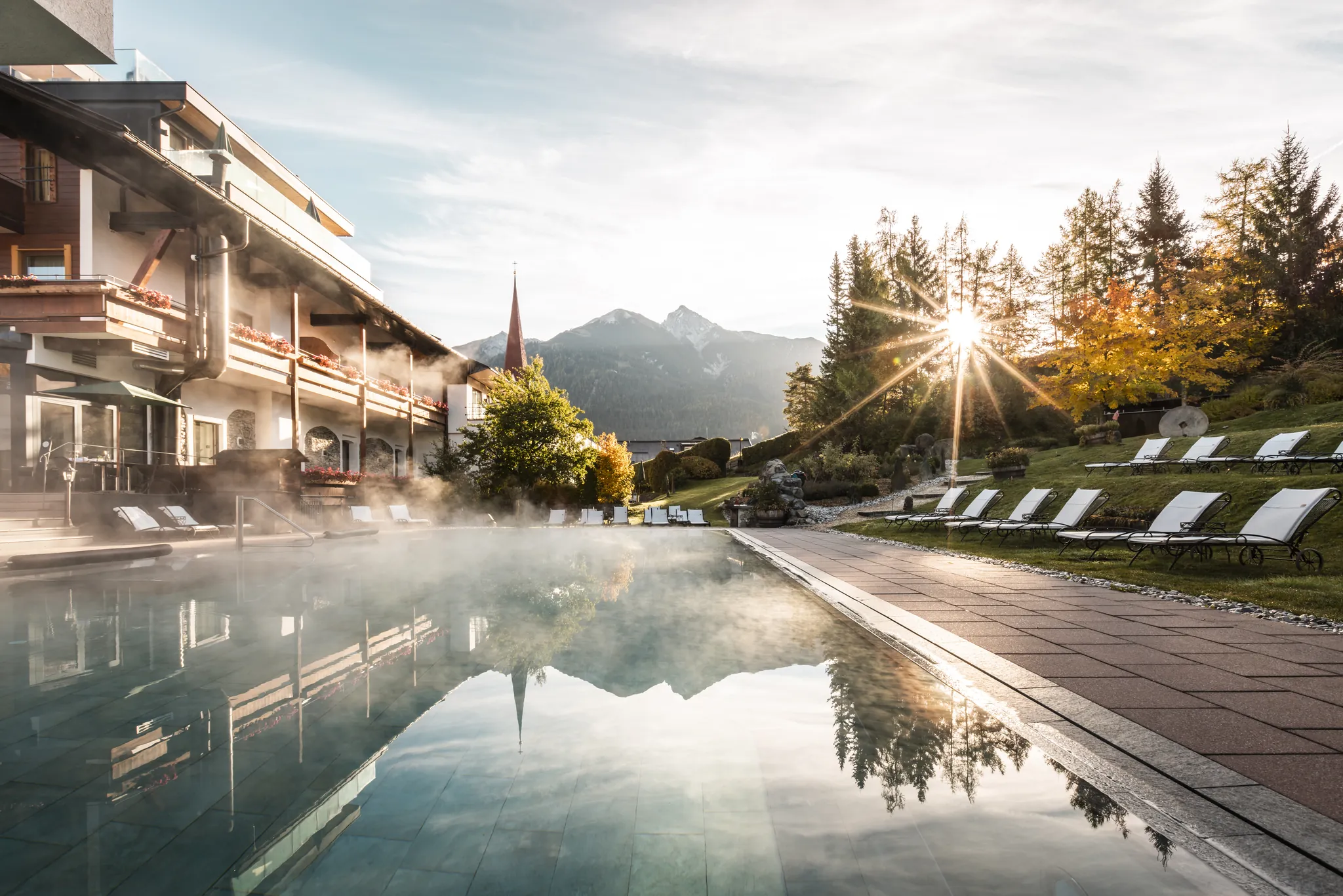 Außenpool des Hotel Klosterbräu im Abendlicht, Spiegelung der Berge im Wasser