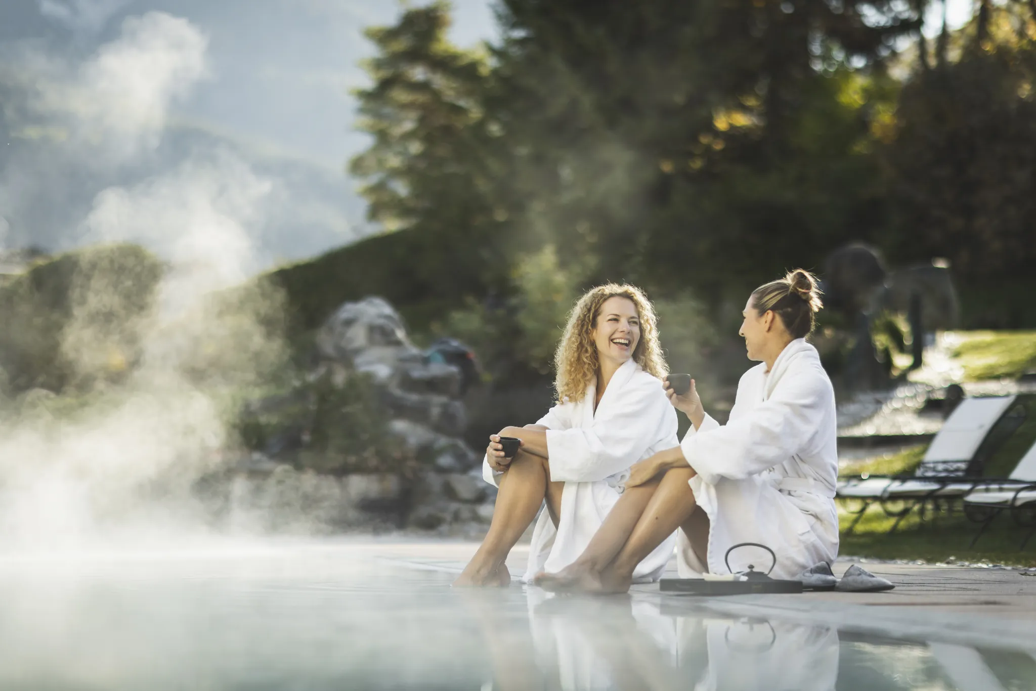 Zwei Freundinnen im Bademantel im dampfenden Außenpool, Hotel Klosterbräu